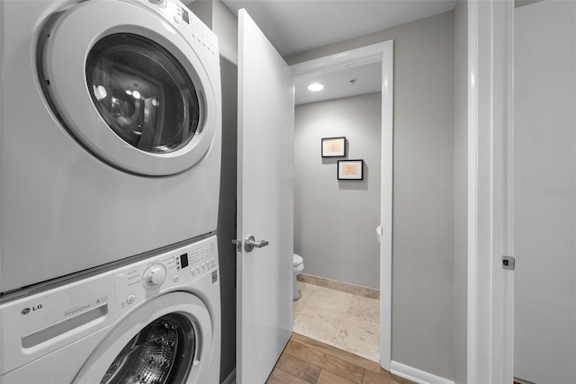 clothes washing area featuring stacked washer / drying machine and tile patterned flooring