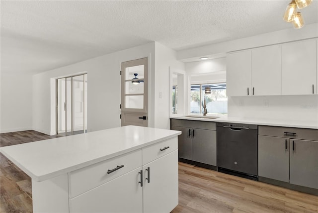 kitchen with stainless steel dishwasher, white cabinetry, sink, and light wood-type flooring