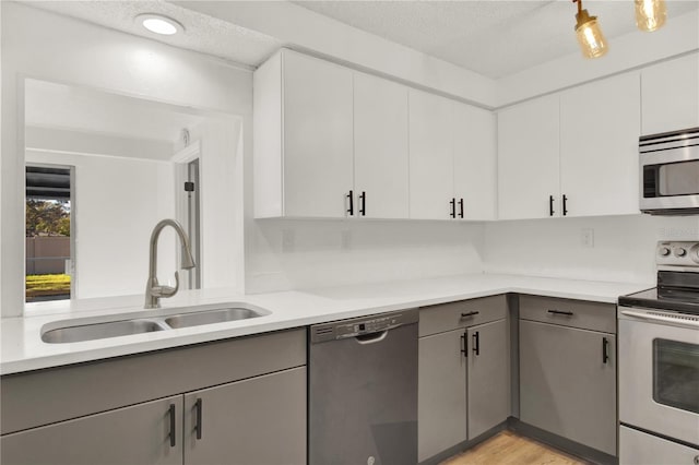 kitchen featuring gray cabinetry, appliances with stainless steel finishes, sink, and a textured ceiling