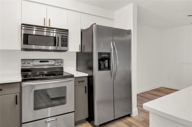 kitchen featuring white cabinetry, stainless steel appliances, a textured ceiling, and light hardwood / wood-style floors