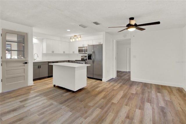 kitchen featuring a center island, white cabinetry, appliances with stainless steel finishes, sink, and light hardwood / wood-style flooring