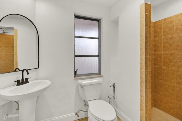 bathroom with tiled shower, sink, and toilet