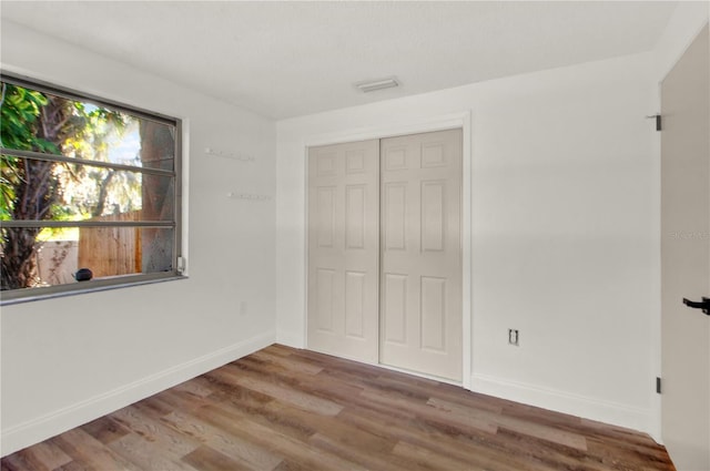 unfurnished bedroom featuring a closet and hardwood / wood-style floors