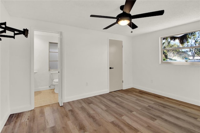 unfurnished bedroom with connected bathroom, ceiling fan, and light hardwood / wood-style flooring