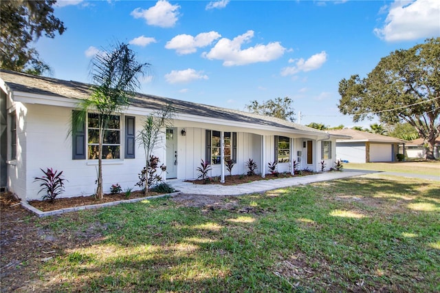 ranch-style house featuring a front yard, covered porch, and a garage