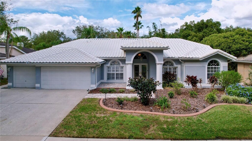 view of front of house with a front yard, a garage, and french doors