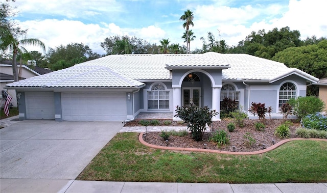 mediterranean / spanish-style home featuring a front yard, a garage, and french doors