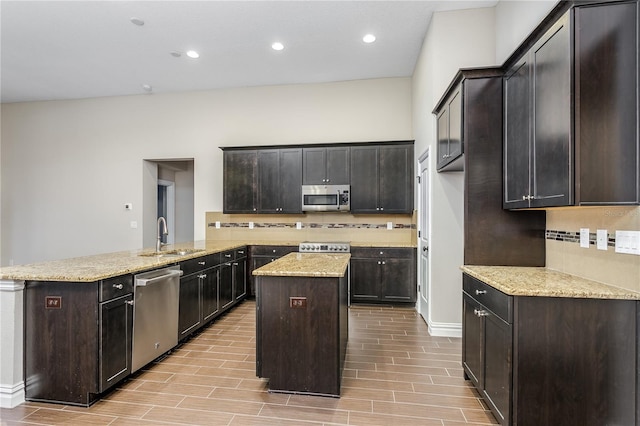 kitchen with sink, a center island, dark brown cabinets, appliances with stainless steel finishes, and light wood-type flooring