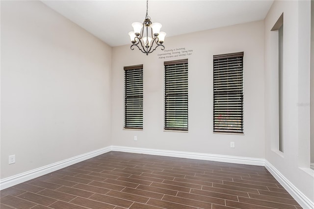 spare room featuring dark wood-type flooring and a chandelier