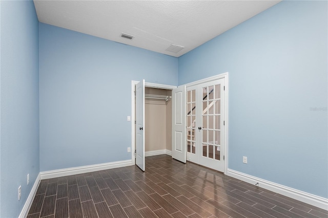 unfurnished room with dark hardwood / wood-style floors, a textured ceiling, and french doors