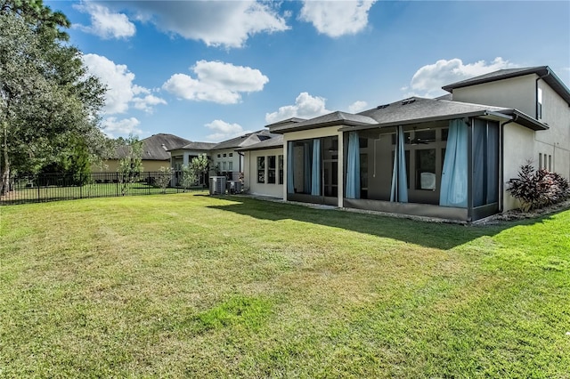 back of house with central AC unit, a sunroom, and a yard