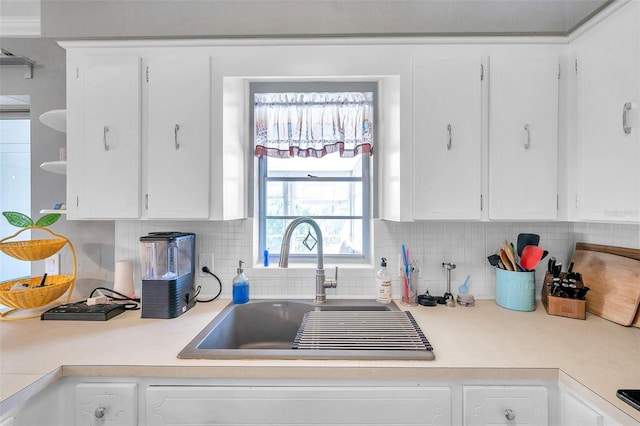 kitchen featuring tasteful backsplash, white cabinetry, and sink