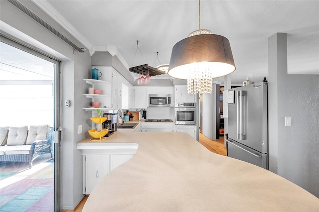 kitchen featuring crown molding, light hardwood / wood-style flooring, stainless steel appliances, and decorative light fixtures