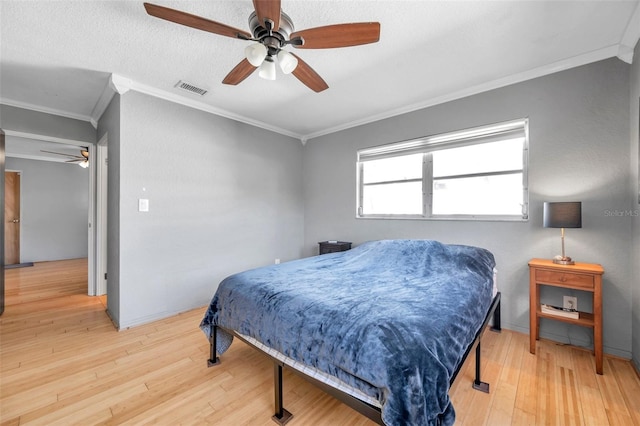 bedroom with a textured ceiling, ceiling fan, light wood-type flooring, and crown molding