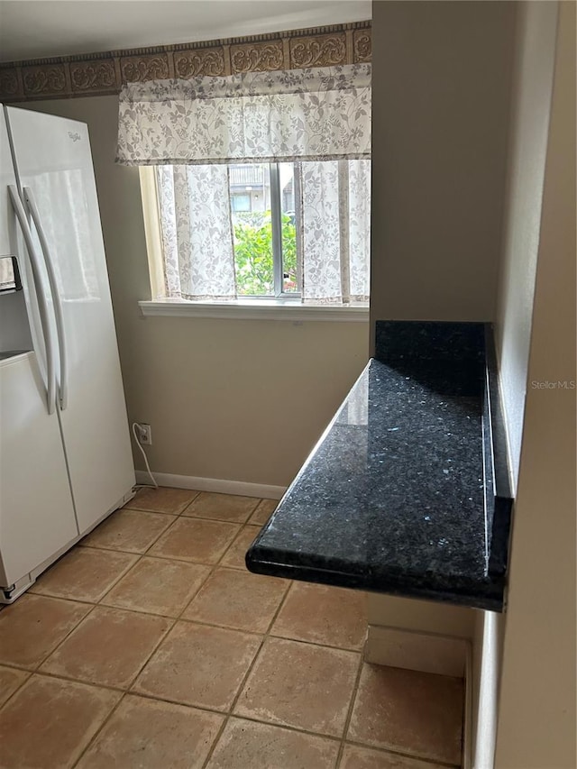 kitchen with white fridge with ice dispenser and light tile patterned floors