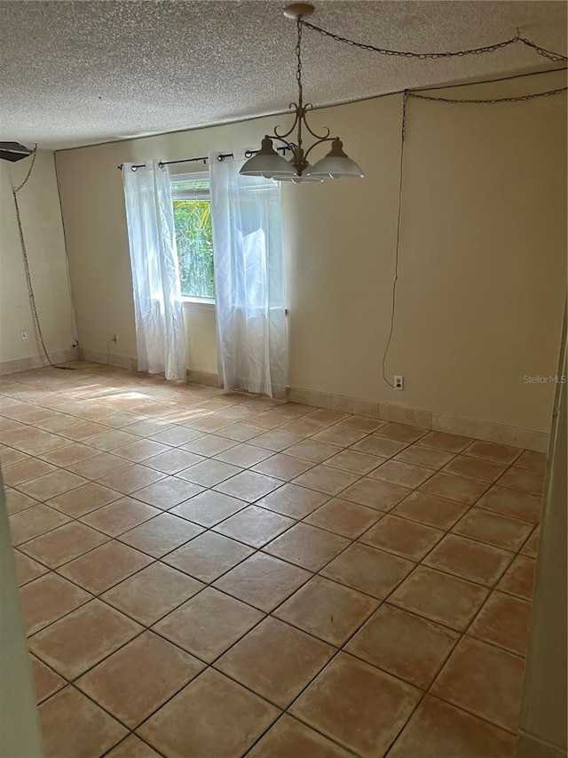 unfurnished room featuring a chandelier and a textured ceiling