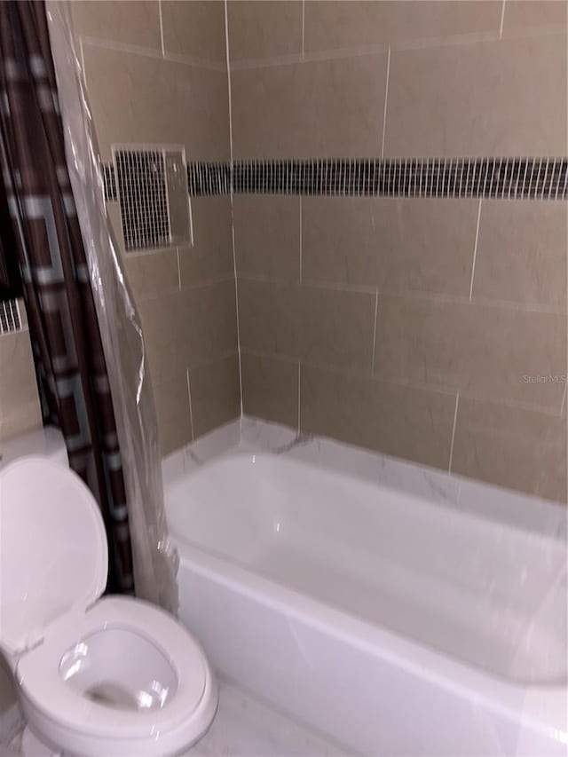 bathroom with toilet and shower / bath combo with shower curtain