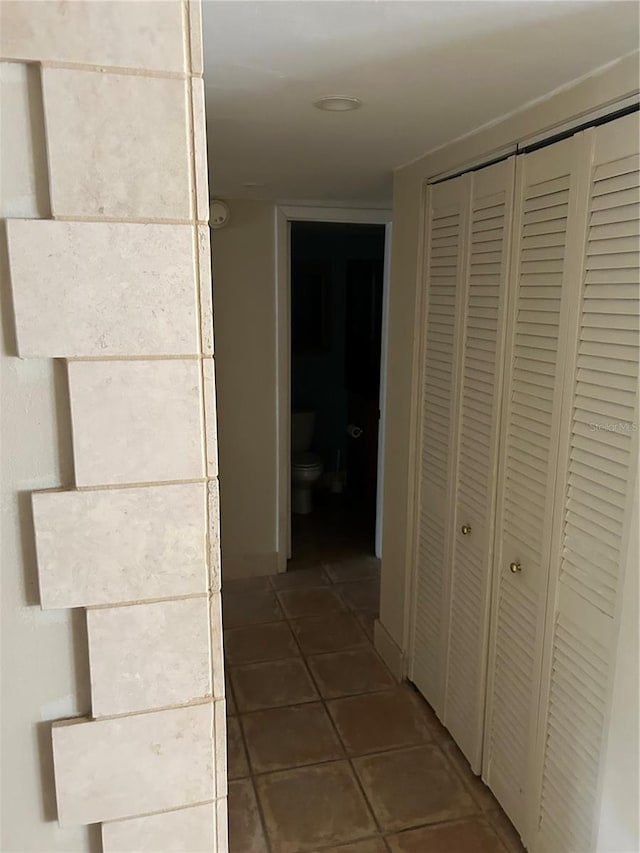 hall featuring dark tile patterned flooring