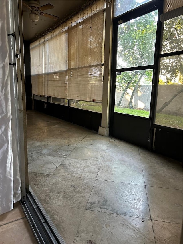 unfurnished sunroom featuring ceiling fan