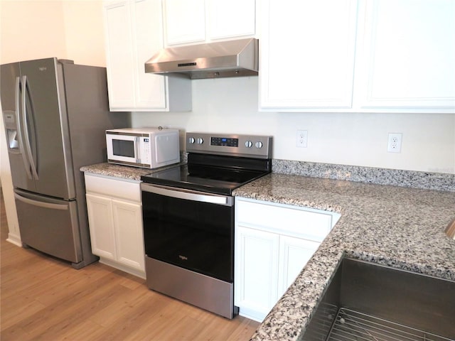 kitchen with white cabinetry, stainless steel appliances, light stone counters, range hood, and light hardwood / wood-style floors