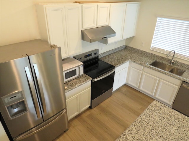 kitchen featuring sink, appliances with stainless steel finishes, white cabinets, exhaust hood, and light wood-type flooring