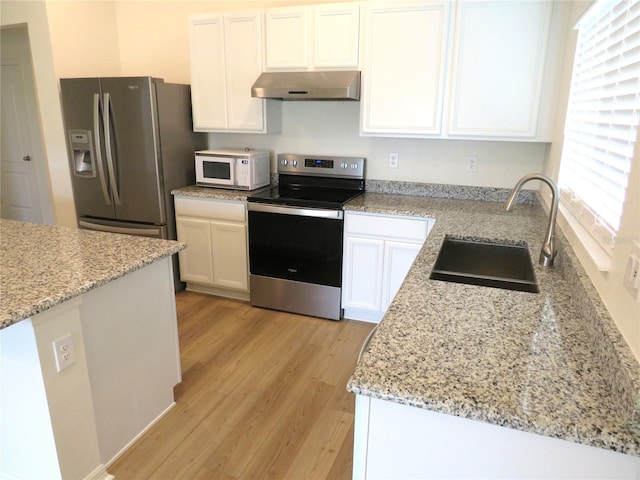 kitchen featuring sink, wall chimney exhaust hood, light hardwood / wood-style floors, white cabinets, and appliances with stainless steel finishes