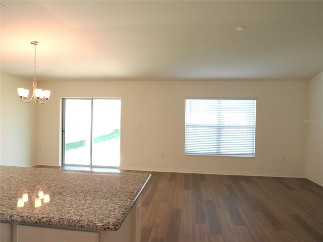 interior space featuring light stone countertops, decorative light fixtures, dark hardwood / wood-style floors, and a chandelier