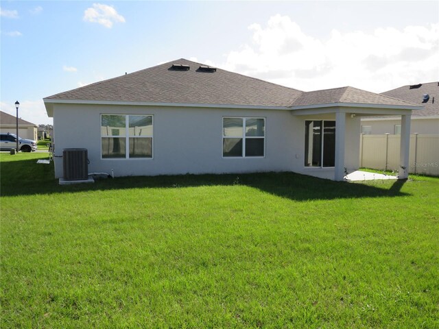 rear view of house with cooling unit and a yard