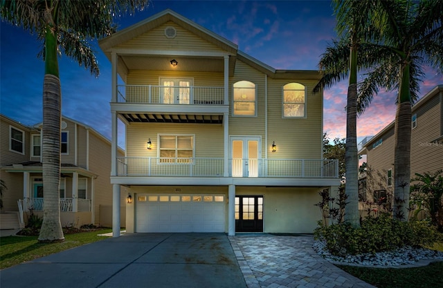 view of front of house featuring french doors, a balcony, and a garage