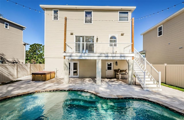 back of house featuring a patio, a balcony, and a pool with hot tub