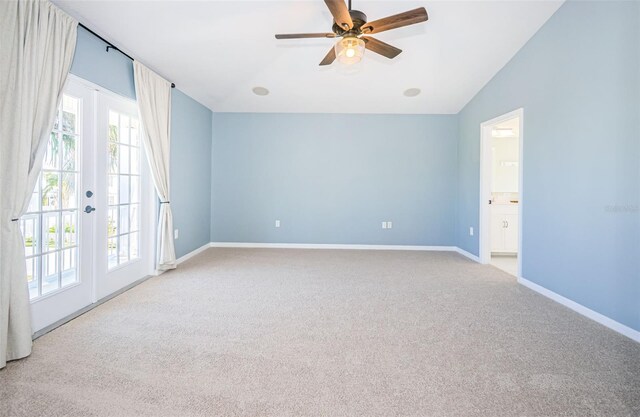 carpeted spare room featuring vaulted ceiling, french doors, and ceiling fan