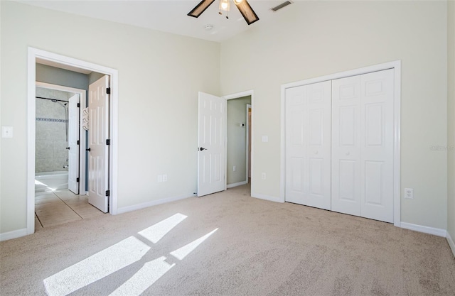 unfurnished bedroom with ceiling fan, ensuite bath, light colored carpet, and a closet