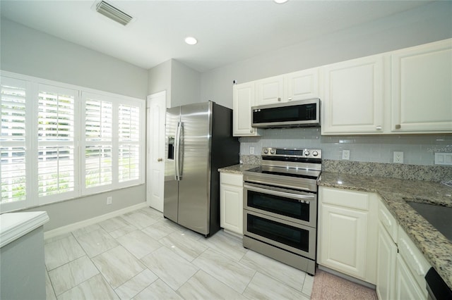 kitchen featuring white cabinets, appliances with stainless steel finishes, tasteful backsplash, and a wealth of natural light