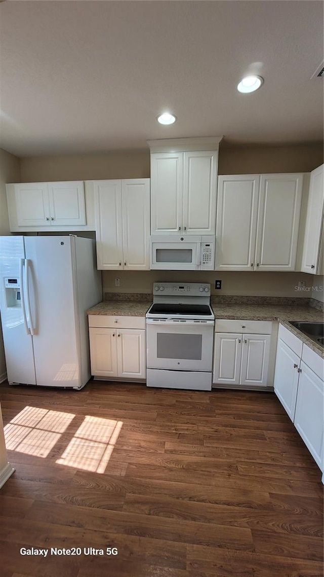 kitchen with dark hardwood / wood-style flooring, white appliances, and white cabinetry