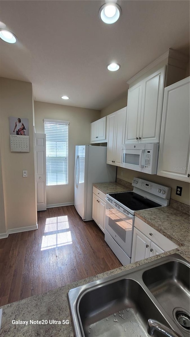 kitchen with white cabinets, white appliances, dark hardwood / wood-style floors, and sink