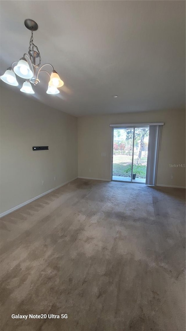 unfurnished room featuring carpet and an inviting chandelier