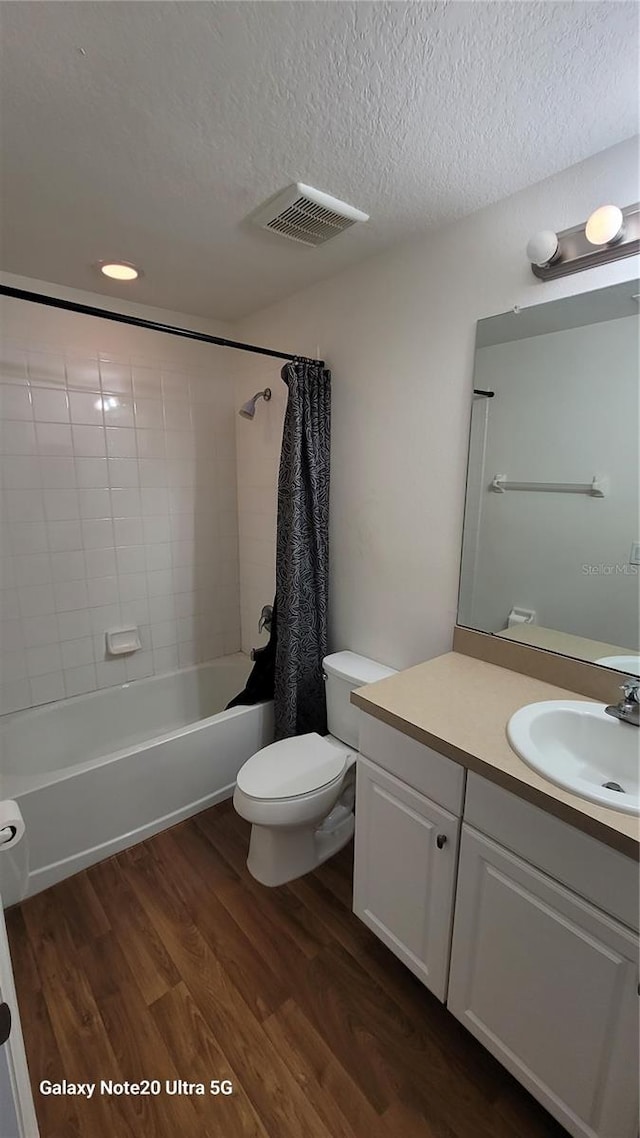 full bathroom with shower / bath combo, vanity, a textured ceiling, hardwood / wood-style floors, and toilet