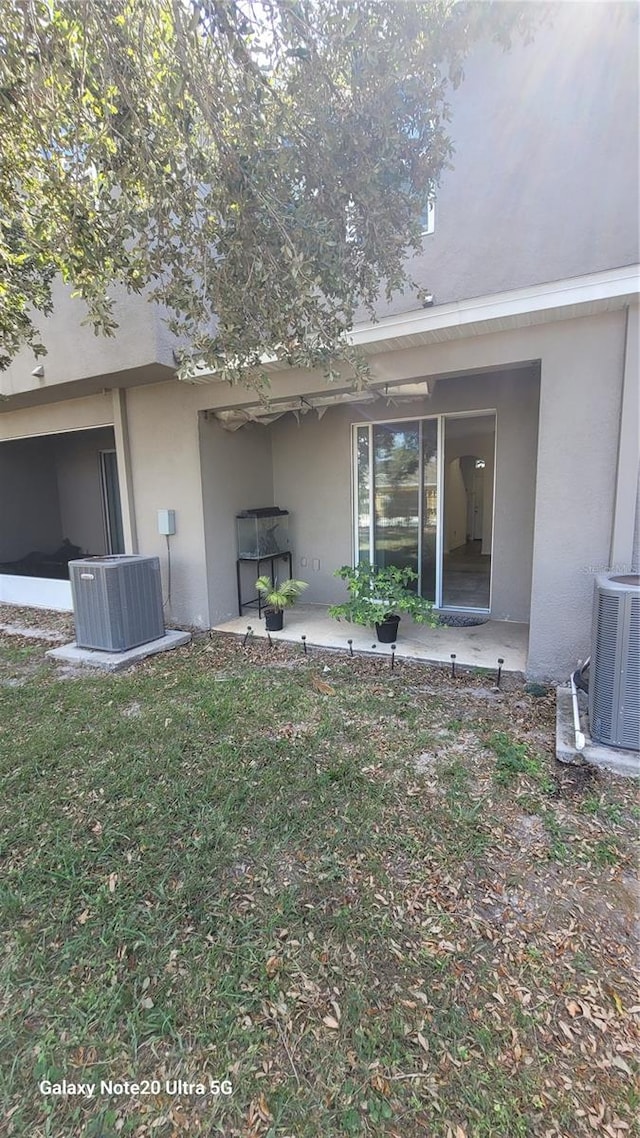 exterior space with central air condition unit, a yard, and a patio