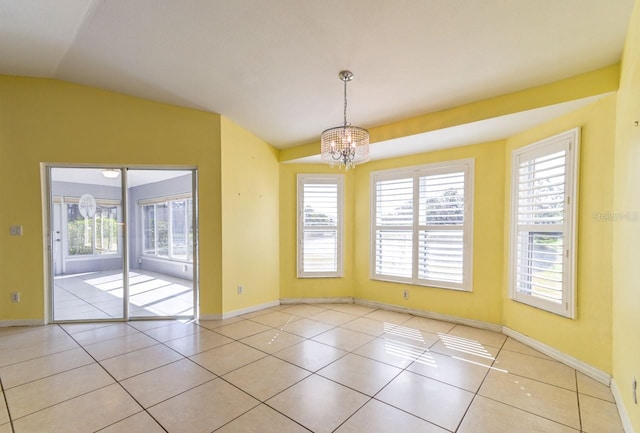 empty room with light tile patterned floors, lofted ceiling, and a notable chandelier