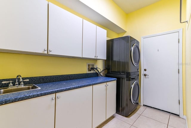 washroom featuring sink, cabinets, light tile patterned floors, and stacked washer / dryer