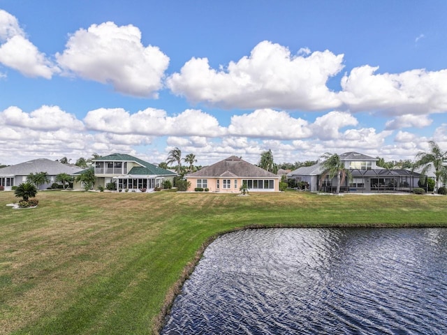 back of property with a lawn and a water view