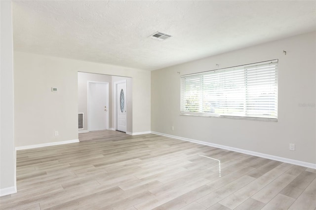 spare room with light hardwood / wood-style flooring and a textured ceiling