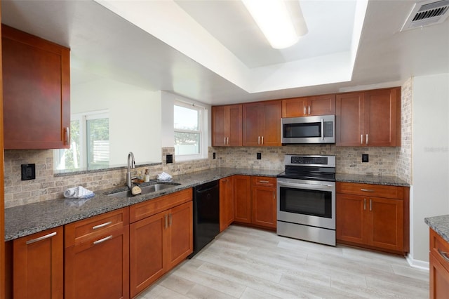 kitchen with tasteful backsplash, sink, light hardwood / wood-style flooring, and appliances with stainless steel finishes