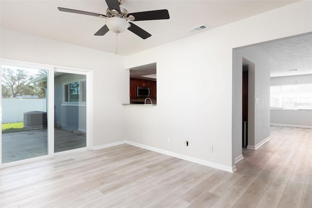 empty room with ceiling fan, a textured ceiling, and light wood-type flooring