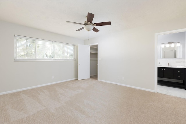 unfurnished bedroom featuring connected bathroom, light colored carpet, and ceiling fan