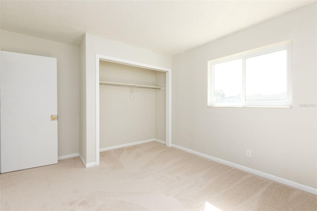 unfurnished bedroom with light carpet and a closet