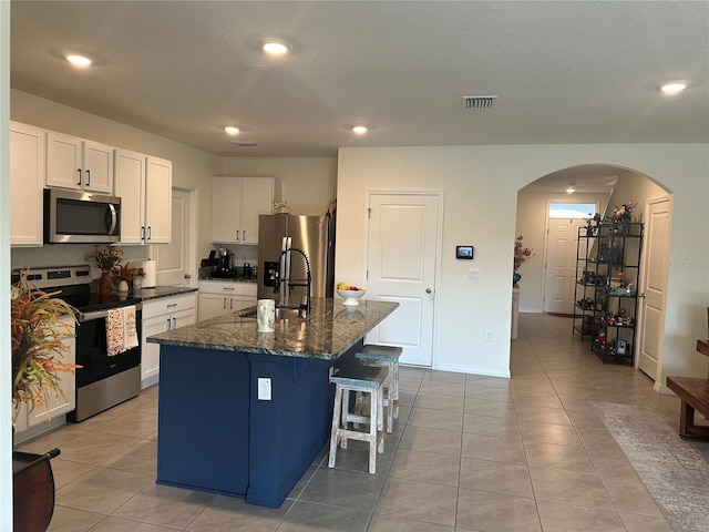 kitchen featuring stainless steel appliances, white cabinetry, a center island with sink, and sink