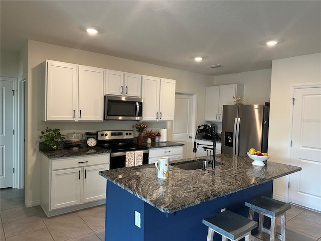 kitchen with white cabinetry, a kitchen island with sink, appliances with stainless steel finishes, and a breakfast bar area