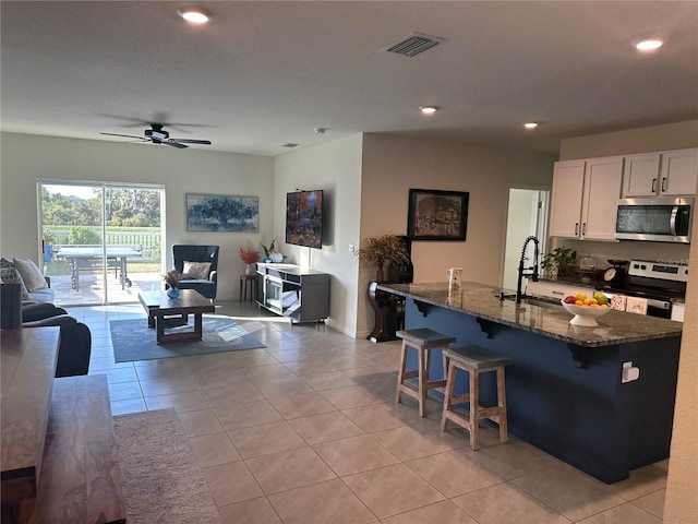 kitchen with appliances with stainless steel finishes, dark stone counters, ceiling fan, sink, and white cabinets