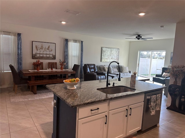 kitchen featuring a kitchen island with sink, sink, dishwasher, white cabinetry, and light tile patterned flooring